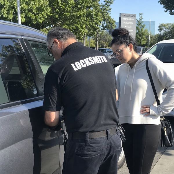 A mobile locksmith technician helping a customer who is locked out of their car in a San Jose parking lot